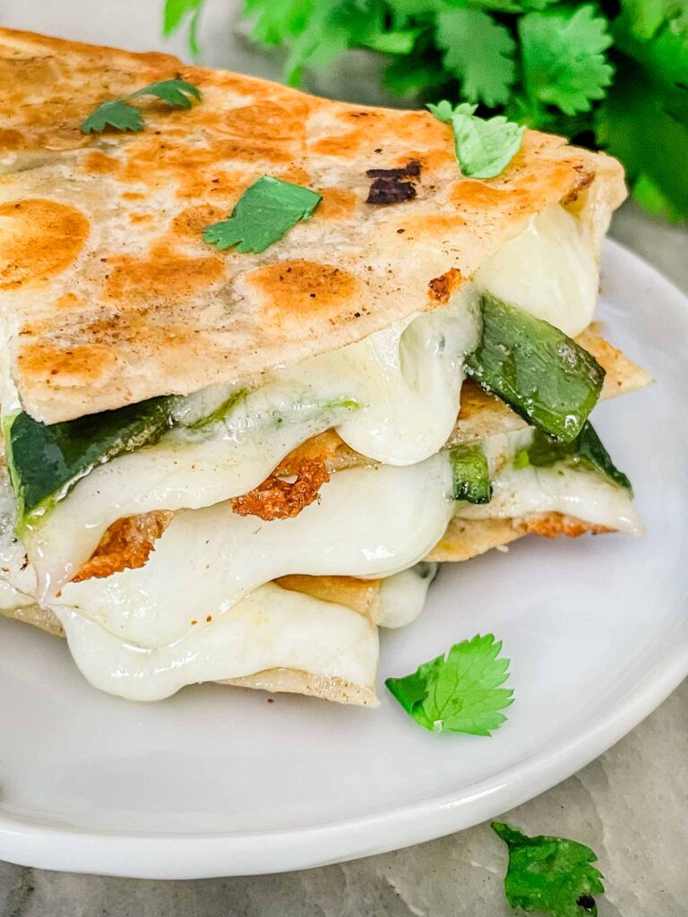 View of the ends of the Chile Relleno Quesadillas stacked up with cheese oozing out of the tortillas