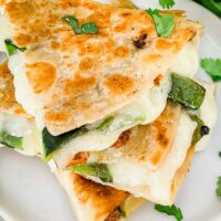 Closer top view of some Chile Relleno Quesadilla pieces stacked in a tower on a white plate