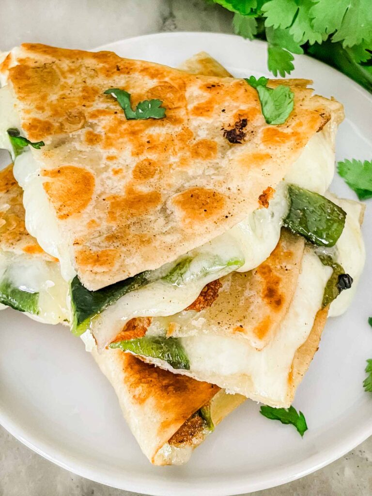 Closer top view of some Chile Relleno Quesadilla pieces stacked in a tower on a white plate