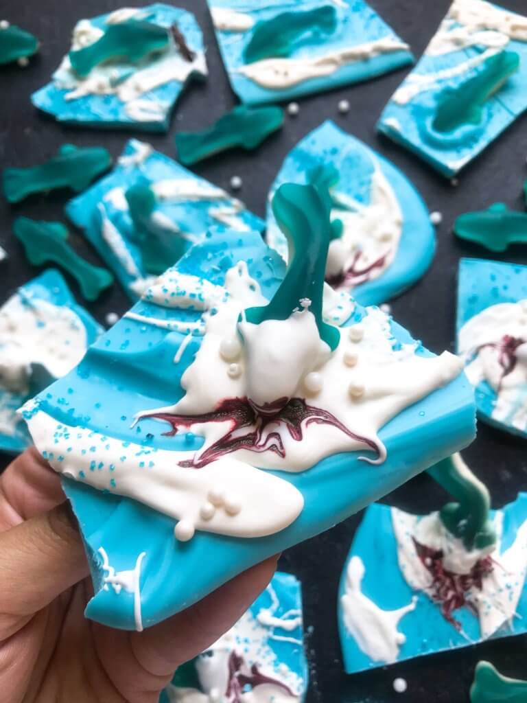Just 10 minutes to make Shark Bark! Candy melts with sprinkles, gummy sharks, and a shark attack scene using red food gel. Gluten free (GF) quick and easy dessert recipe for shark or ocean party. Shark Week Shark Bark | Three Olives Branch | www.threeolivesbranch.com #sharkweek #ocean #sharkattack