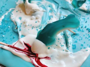 Just 10 minutes to make Shark Bark! Candy melts with sprinkles, gummy sharks, and a shark attack scene using red food gel. Gluten free (GF) quick and easy dessert recipe for shark or ocean party. Shark Week Shark Bark | Three Olives Branch | www.threeolivesbranch.com #sharkweek #ocean #sharkattack