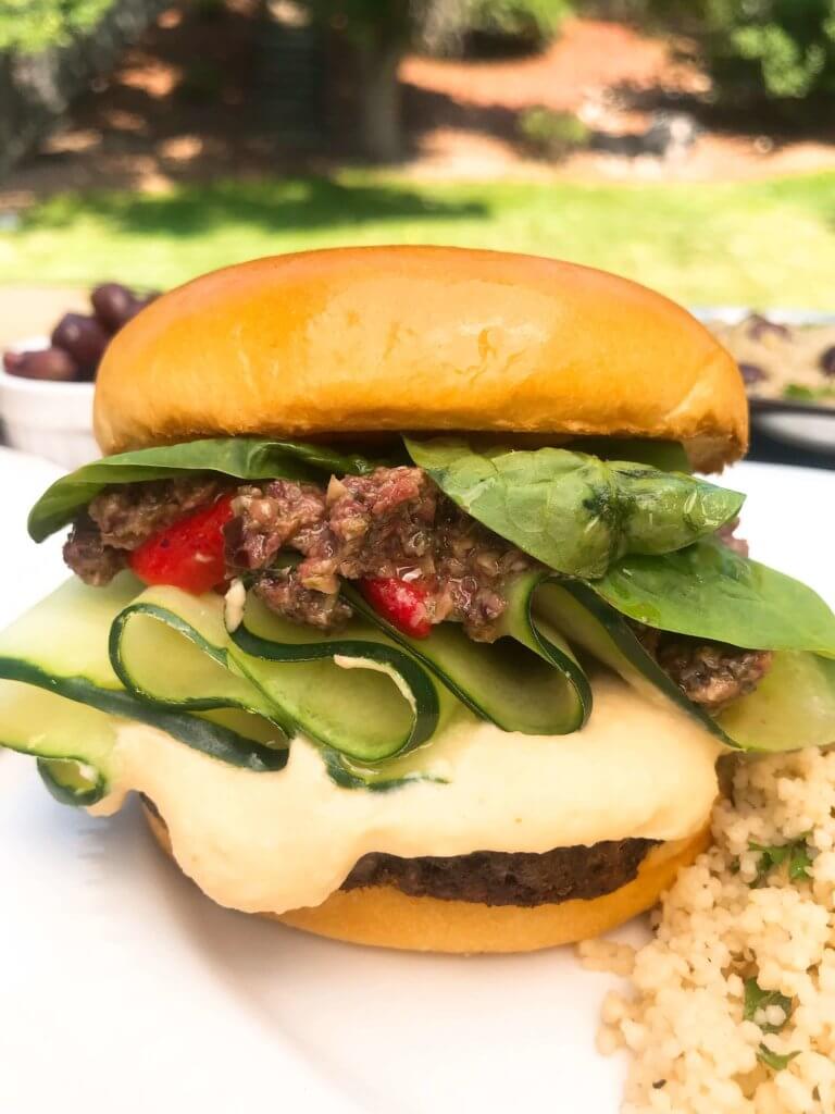 Vegan burgers topped with cucumber, olive tapenade, roasted red peppers, hummus, and spinach. Made with MorningStar Farms® Meat Lovers Burgers, these burgers are ready in just 20 minutes. Vegan Mediterranean Burgers #grilling #MorningStarFarms #MakeRoomOnYourGrill #ad