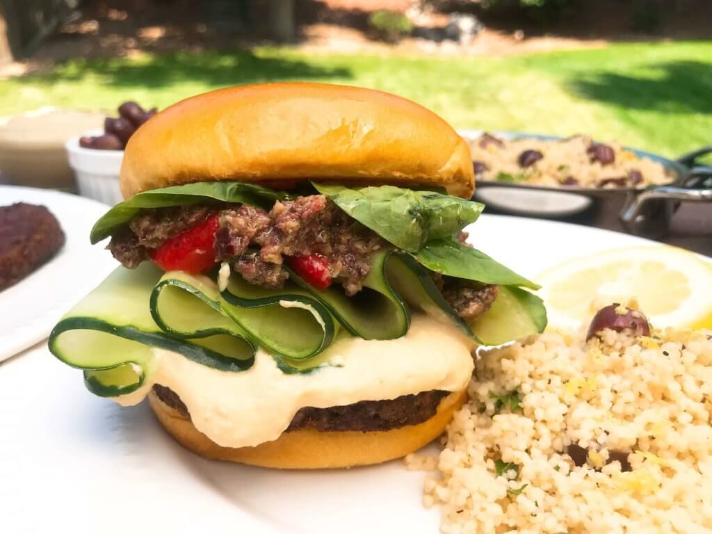 Vegan burgers topped with cucumber, olive tapenade, roasted red peppers, hummus, and spinach. Made with MorningStar Farms® Meat Lovers Burgers, these burgers are ready in just 20 minutes. Vegan Mediterranean Burgers #grilling #MorningStarFarms #MakeRoomOnYourGrill #ad