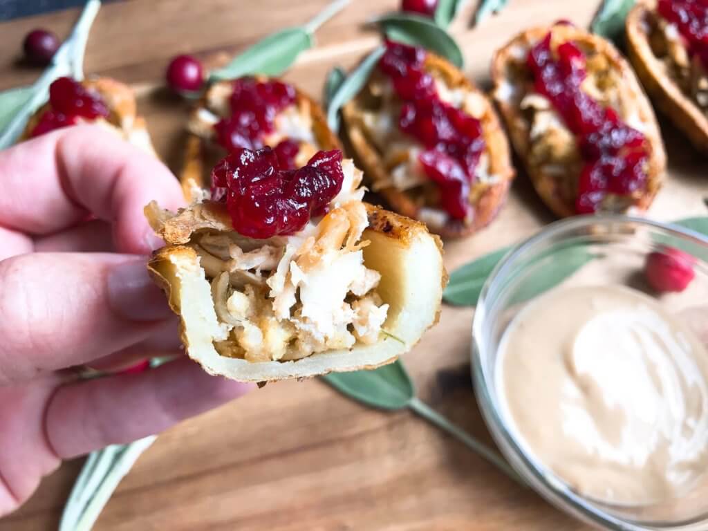 A fun recipe to use leftover Thanksgiving food! Stuffing, turkey, and cheese are layered in a potato skin shell and topped with cranberry sauce and gravy. Use any leftover like green bean casserole! Thanksgiving Leftovers Potato Skins | Three Olives Branch | www.threeolivesbranch.com #thanksgivingrecipes #thanksgivingleftovers