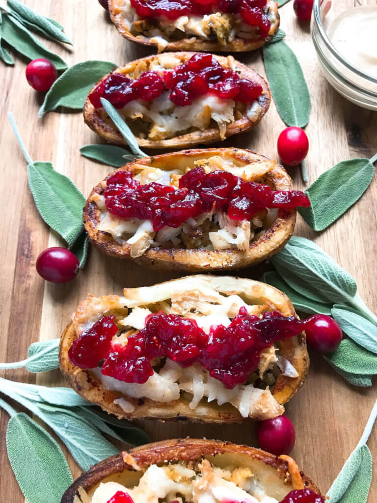 A fun recipe to use leftover Thanksgiving food! Stuffing, turkey, and cheese are layered in a potato skin shell and topped with cranberry sauce and gravy. Use any leftover like green bean casserole! Thanksgiving Leftovers Potato Skins | Three Olives Branch | www.threeolivesbranch.com #thanksgivingrecipes #thanksgivingleftovers