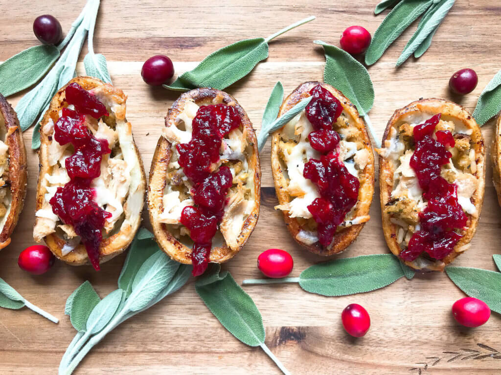 A fun recipe to use leftover Thanksgiving food! Stuffing, turkey, and cheese are layered in a potato skin shell and topped with cranberry sauce and gravy. Use any leftover like green bean casserole! Thanksgiving Leftovers Potato Skins | Three Olives Branch | www.threeolivesbranch.com #thanksgivingrecipes #thanksgivingleftovers