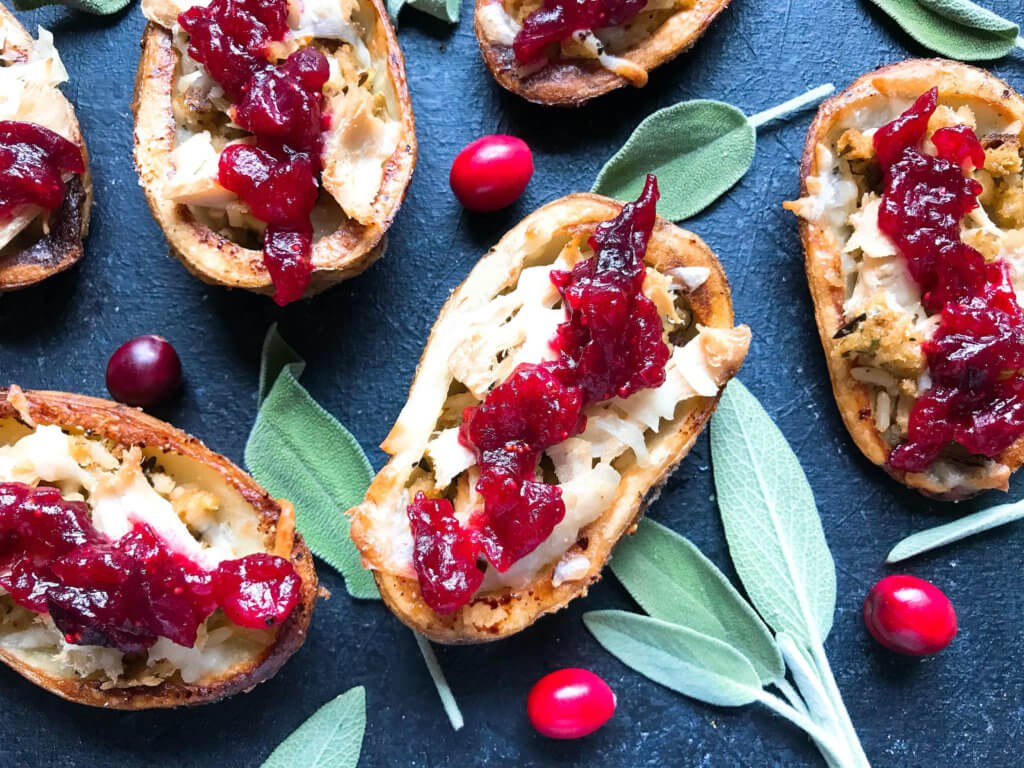 A fun recipe to use leftover Thanksgiving food! Stuffing, turkey, and cheese are layered in a potato skin shell and topped with cranberry sauce and gravy. Use any leftover like green bean casserole! Thanksgiving Leftovers Potato Skins | Three Olives Branch | www.threeolivesbranch.com #thanksgivingrecipes #thanksgivingleftovers