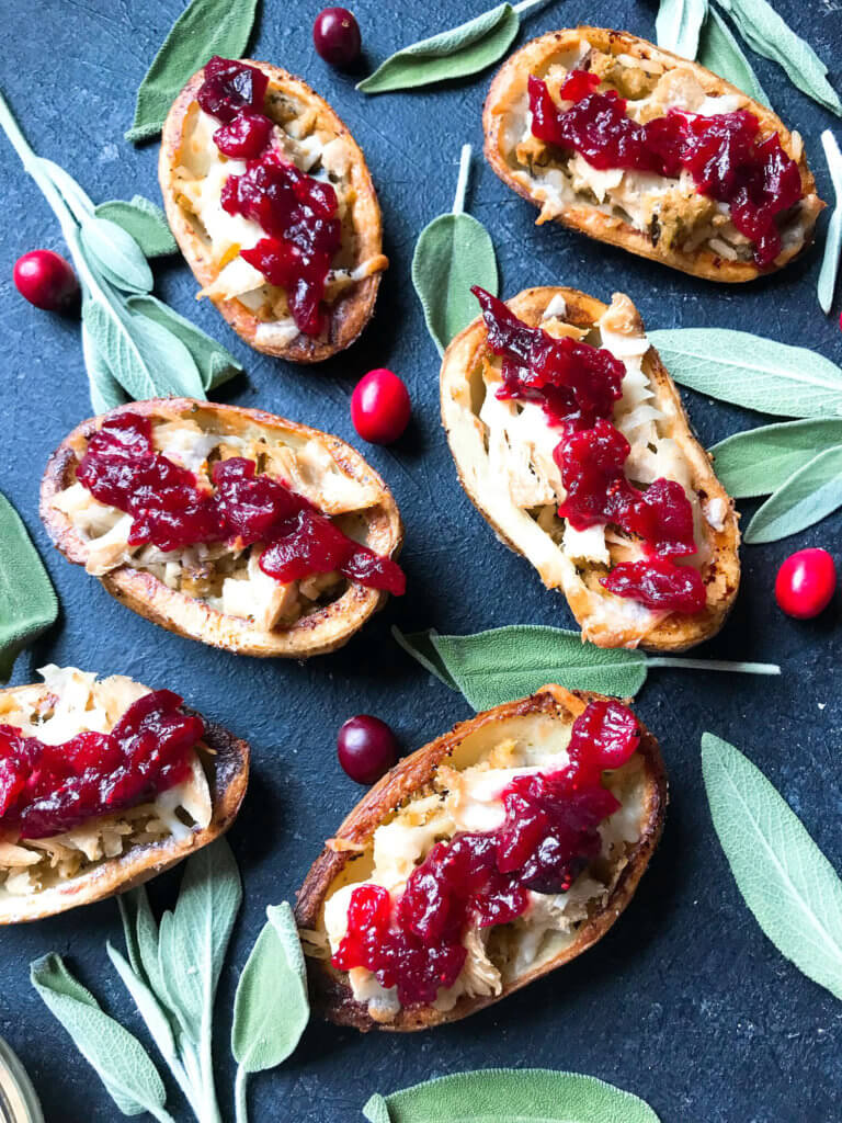 A fun recipe to use leftover Thanksgiving food! Stuffing, turkey, and cheese are layered in a potato skin shell and topped with cranberry sauce and gravy. Use any leftover like green bean casserole! Thanksgiving Leftovers Potato Skins | Three Olives Branch | www.threeolivesbranch.com #thanksgivingrecipes #thanksgivingleftovers