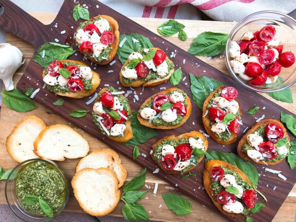 Caprese Pesto Crostini surrounded by basil