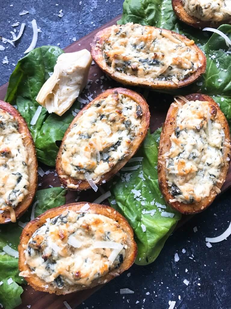 Classic spinach artichoke dip stuffed in potato skin shells. Great recipe for game day, holiday entertaining, and party appetizer. Vegetarian and gluten free. Spinach Artichoke Dip Potato Skins #appetizer #spinachartichokedip