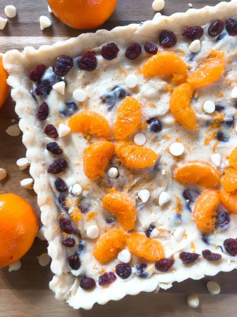 A fast and easy dessert recipe ready in just 30 minutes. Cranberry Orange Tart has a soft cookie shell with a cream cheese filling mixed with dried cranberries, orange zest, and white chocolate chips. #christmasdessert #holidayrecipes #holidaybaking #fruittart