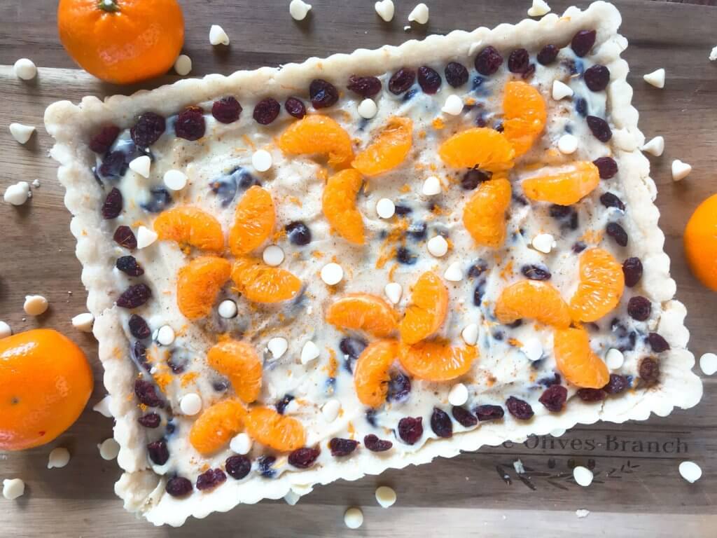 A fast and easy dessert recipe ready in just 30 minutes. Cranberry Orange Tart has a soft cookie shell with a cream cheese filling mixed with dried cranberries, orange zest, and white chocolate chips. #christmasdessert #holidayrecipes #holidaybaking #fruittart