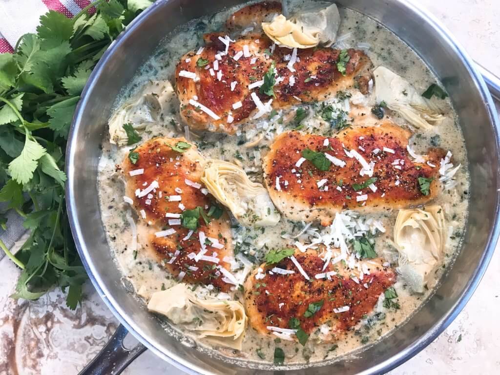 One pot Creamy Skillet Spinach Artichoke Chicken ready in 30 minutes for a fast and easy dinner recipe. Chicken is browned and served in a creamy Parmesan cheese sauce with spinach and artichoke hearts. Gluten free. #chickenrecipes #glutenfreerecipes #chickendinner