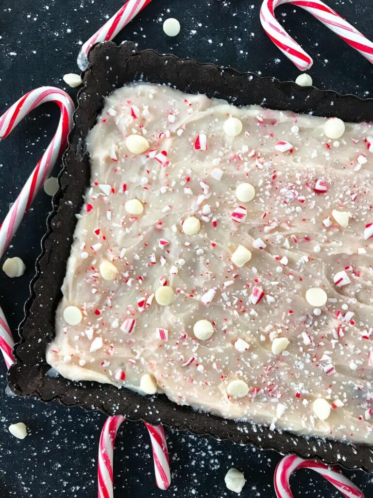 A simple Christmas baking recipe ready in 30 minutes. Chocolate Peppermint Tart is a soft cocoa shell filled with a peppermint cream cheese filling and topped with crushed candy canes and white chocolate. Fast and easy vegetarian holiday recipe. #chocolatepeppermint #christmasdessert #peppermintrecipes