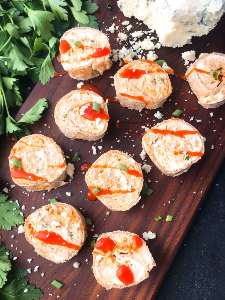 Classic buffalo chicken wing flavors in a finger food appetizer. Buffalo Chicken Pinwheel Roll Ups filled with cream cheese, blue cheese, shredded chicken, and buffalo wing sauce rolled up in a tortilla. Simple, fast, and easy game day tailgating recipe. #gamedayrecipes #buffalowing #buffalochicken