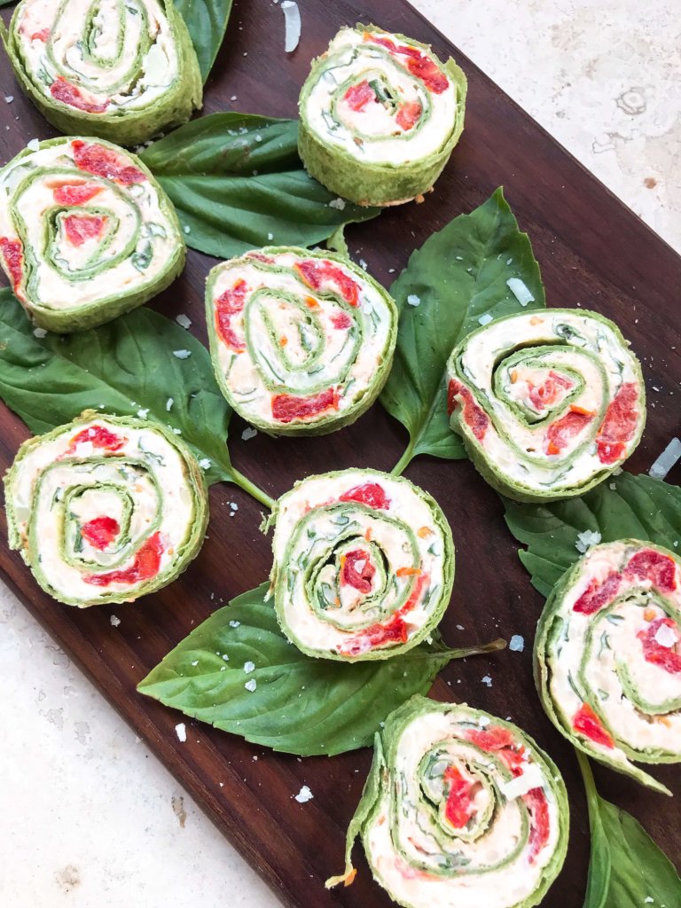 Fast and simple appetizer recipe. Caprese Pinwheel Roll Ups are filled with cream cheese, tomatoes, fresh basil, mozzarella, and Parmesan rolled up in tortillas and sliced into party finger food bites. Vegetarian. #caprese #appetizerrecipes #vegetarianrecipes