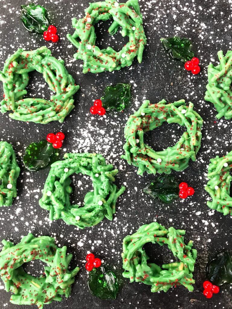 No Bake Christmas Wreath Cookies on a black background with glass holly leaves