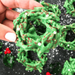 Pin of a hand holding a No Bake Christmas Wreath Cookie with title at bottom