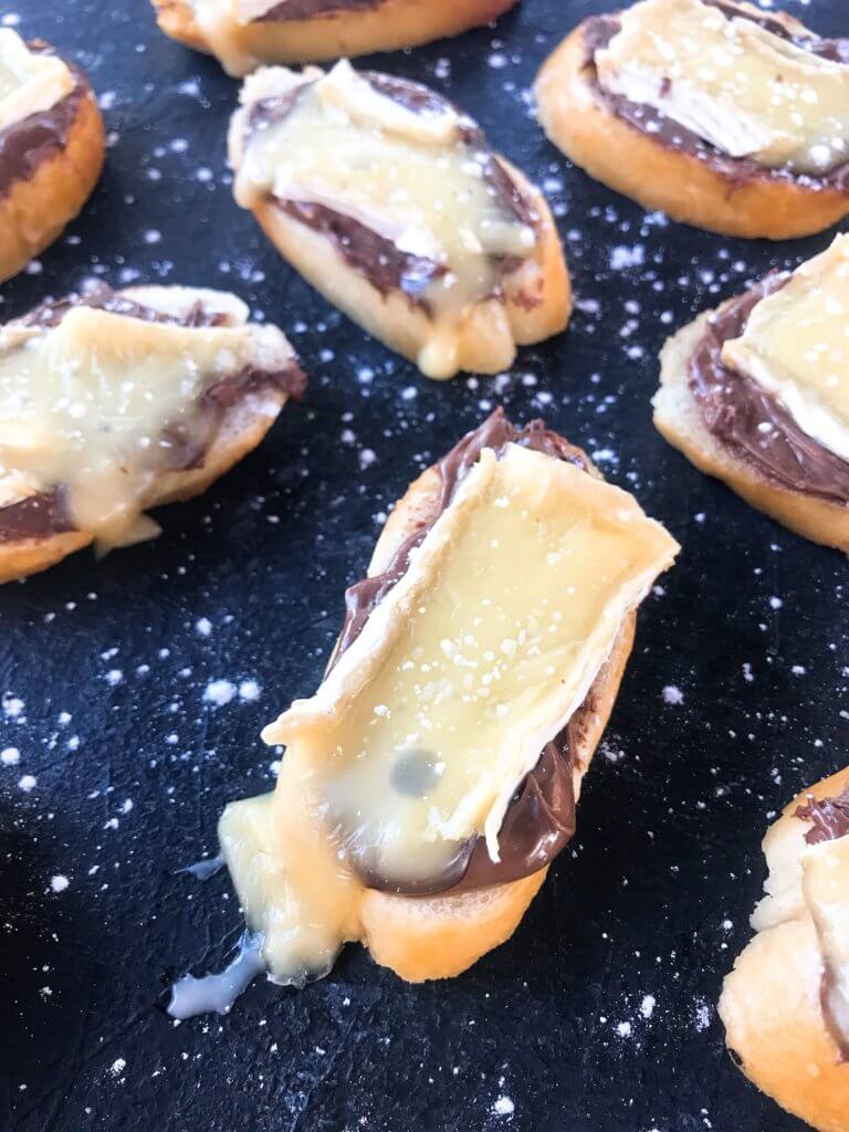 A quick and simple party appetizer recipe ready in less than 30 minutes. Brie cheese and chocolate hazelnut spread with salt on toasted bread slices. Nutella and Brie Crostini are vegetarian finger food with a sweet and salty, savory flavor. 