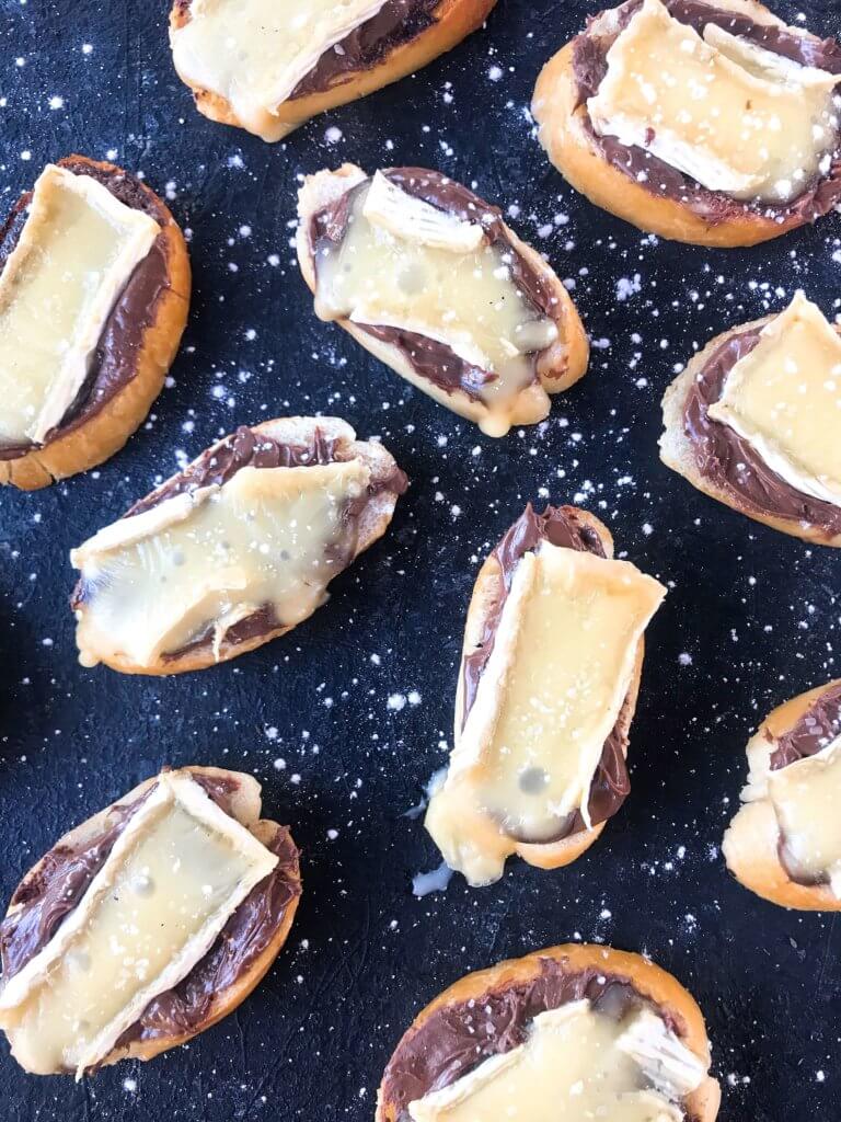 A quick and simple party appetizer recipe ready in less than 30 minutes. Brie cheese and chocolate hazelnut spread with salt on toasted bread slices. Nutella and Brie Crostini are vegetarian finger food with a sweet and salty, savory flavor. 