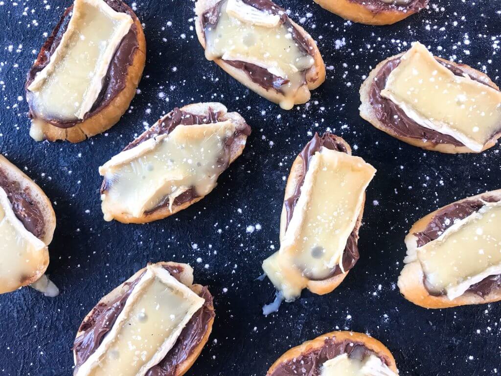 A quick and simple party appetizer recipe ready in less than 30 minutes. Brie cheese and chocolate hazelnut spread with salt on toasted bread slices. Nutella and Brie Crostini are vegetarian finger food with a sweet and salty, savory flavor. 