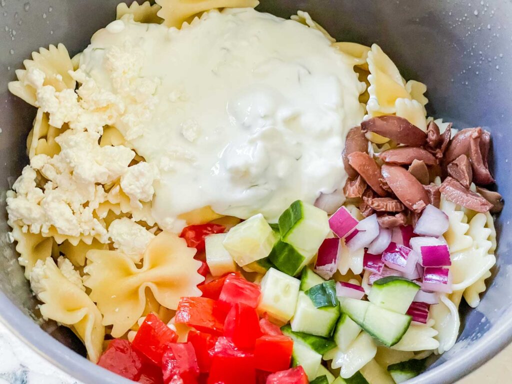 The ingredients needed for the pasta salad in a bowl before mixing