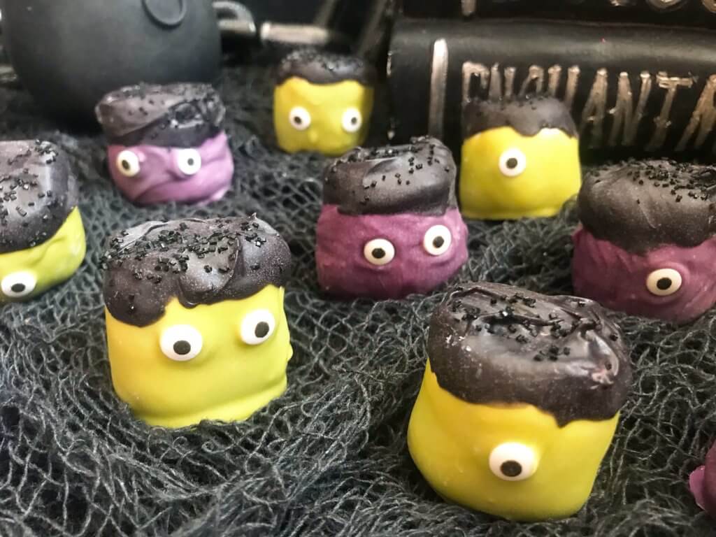 Simple and easy Halloween treat dessert recipe. Halloween Candy Dipped Monster Marshmallows are large marshmallows dunked in colored candy melts with sprinkles and candy eyes for your Halloween party. #halloweenfood #halloweenrecipes #halloweenparty #monsterparty