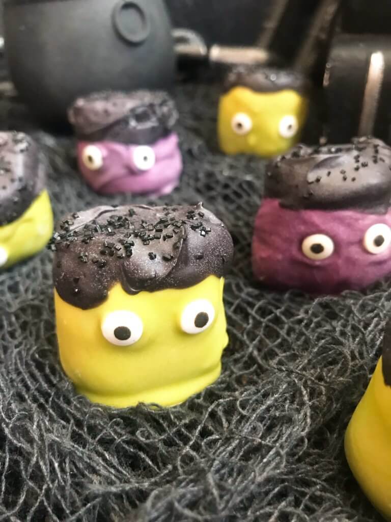 Simple and easy Halloween treat dessert recipe. Halloween Candy Dipped Monster Marshmallows are large marshmallows dunked in colored candy melts with sprinkles and candy eyes for your Halloween party. #halloweenfood #halloweenrecipes #halloweenparty #monsterparty