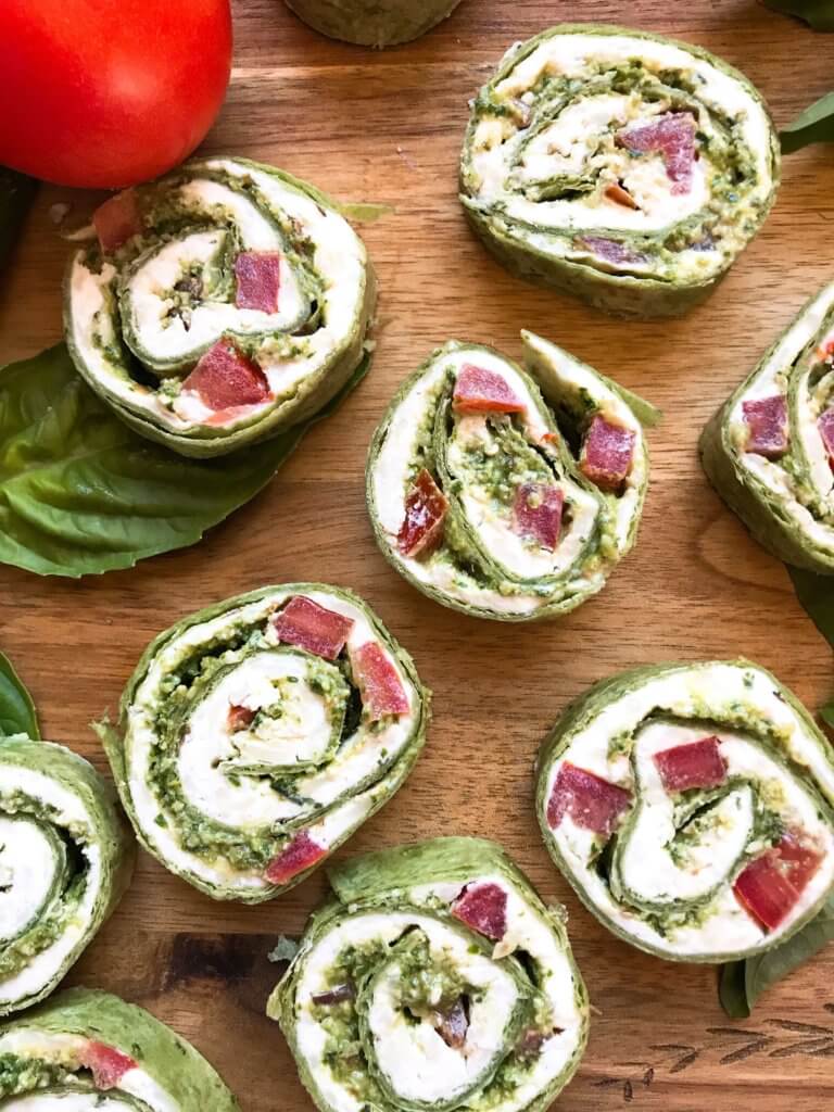 Fast and simple party appetizer recipe. Vegetarian Caprese Pesto Pinwheels Roll Ups are made of cream cheese, mozzarella, Parmesan, basil pesto, and tomatoes rolled in a flour tortilla. Easy finger food for entertaining or game day. #basilpesto #caprese #pinwheels #appetizers 