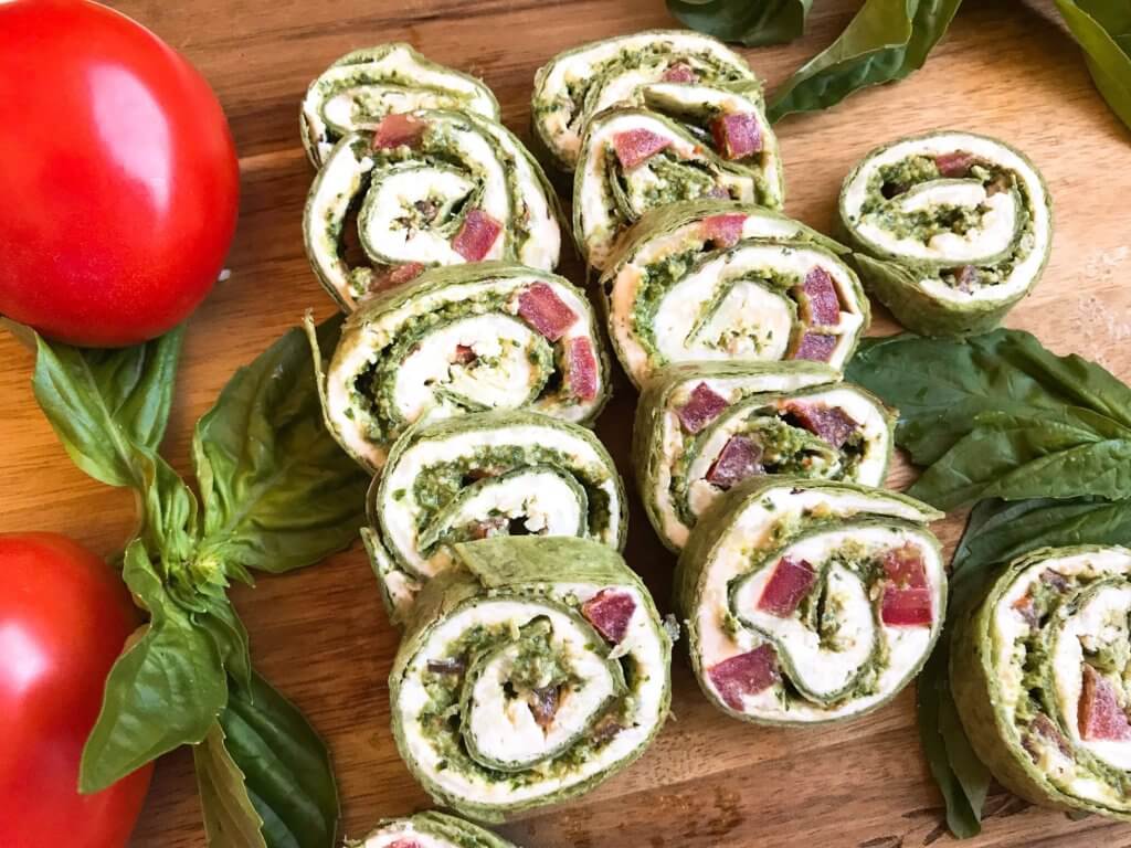 Fast and simple party appetizer recipe. Vegetarian Caprese Pesto Pinwheels Roll Ups are made of cream cheese, mozzarella, Parmesan, basil pesto, and tomatoes rolled in a flour tortilla. Easy finger food for entertaining or game day. #basilpesto #caprese #pinwheels #appetizers 