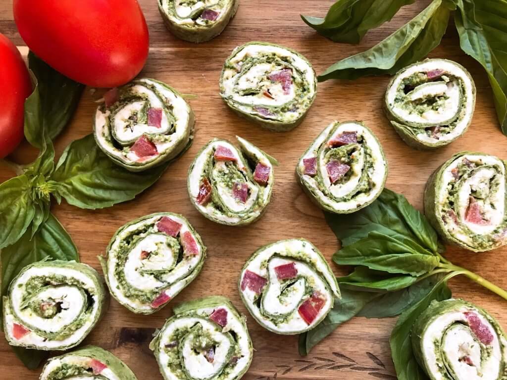 Fast and simple party appetizer recipe. Vegetarian Caprese Pesto Pinwheels Roll Ups are made of cream cheese, mozzarella, Parmesan, basil pesto, and tomatoes rolled in a flour tortilla. Easy finger food for entertaining or game day. #basilpesto #caprese #pinwheels #appetizers 