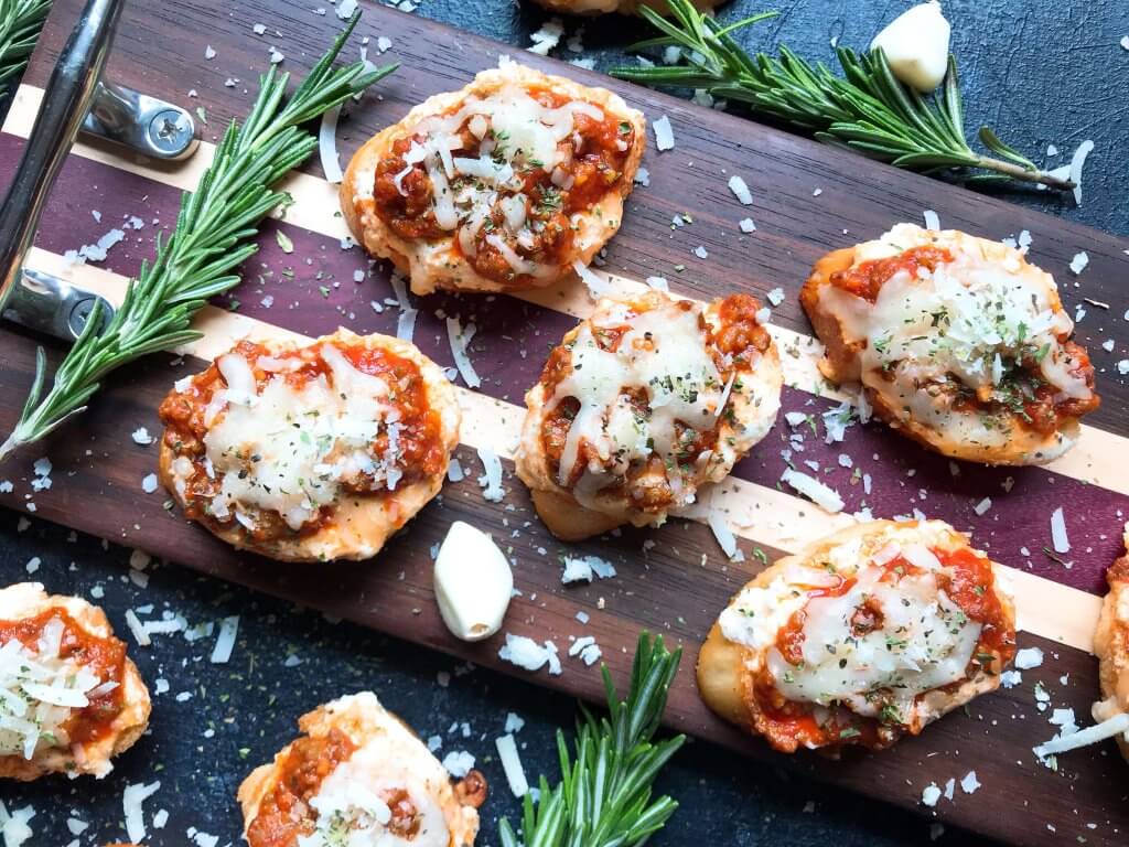 Quick and simple Simple Beef Lasagna Crostini are ready in less than 30 minutes. Ground beef is mixed in marinara and layered with three cheeses on bite sized appetizer toasts. Ricotta, mozzarella, and Parmesan cheeses make this a great entertaining or party food for game day and holidays. #lasagna #beefappetizer #partyfood