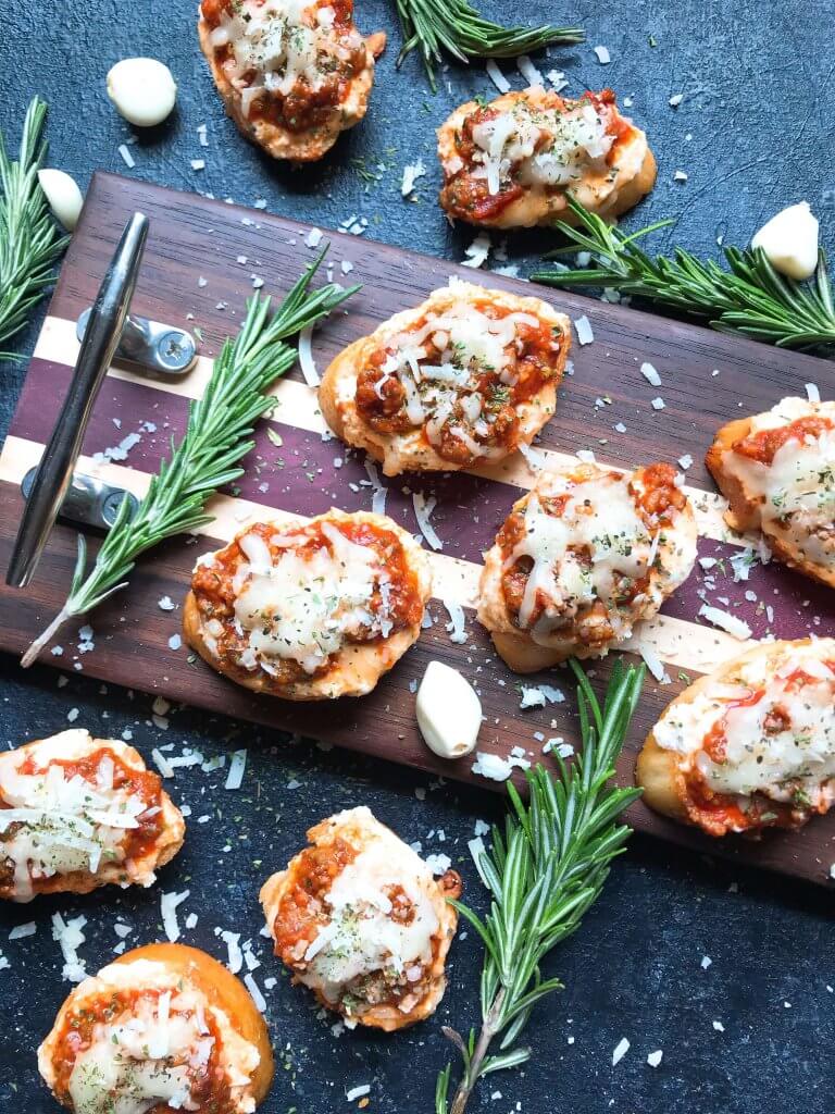 Quick and simple Simple Beef Lasagna Crostini are ready in less than 30 minutes. Ground beef is mixed in marinara and layered with three cheeses on bite sized appetizer toasts. Ricotta, mozzarella, and Parmesan cheeses make this a great entertaining or party food for game day and holidays. #lasagna #beefappetizer #partyfood