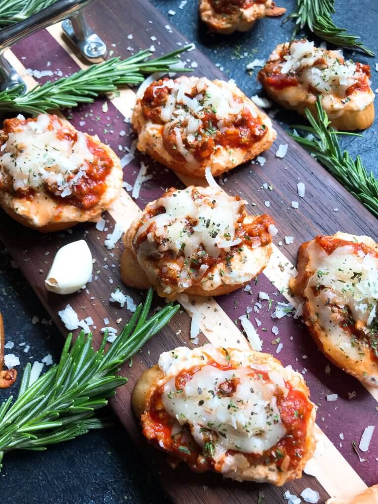 Quick and simple Simple Beef Lasagna Crostini are ready in less than 30 minutes. Ground beef is mixed in marinara and layered with three cheeses on bite sized appetizer toasts. Ricotta, mozzarella, and Parmesan cheeses make this a great entertaining or party food for game day and holidays. #lasagna #beefappetizer #partyfood