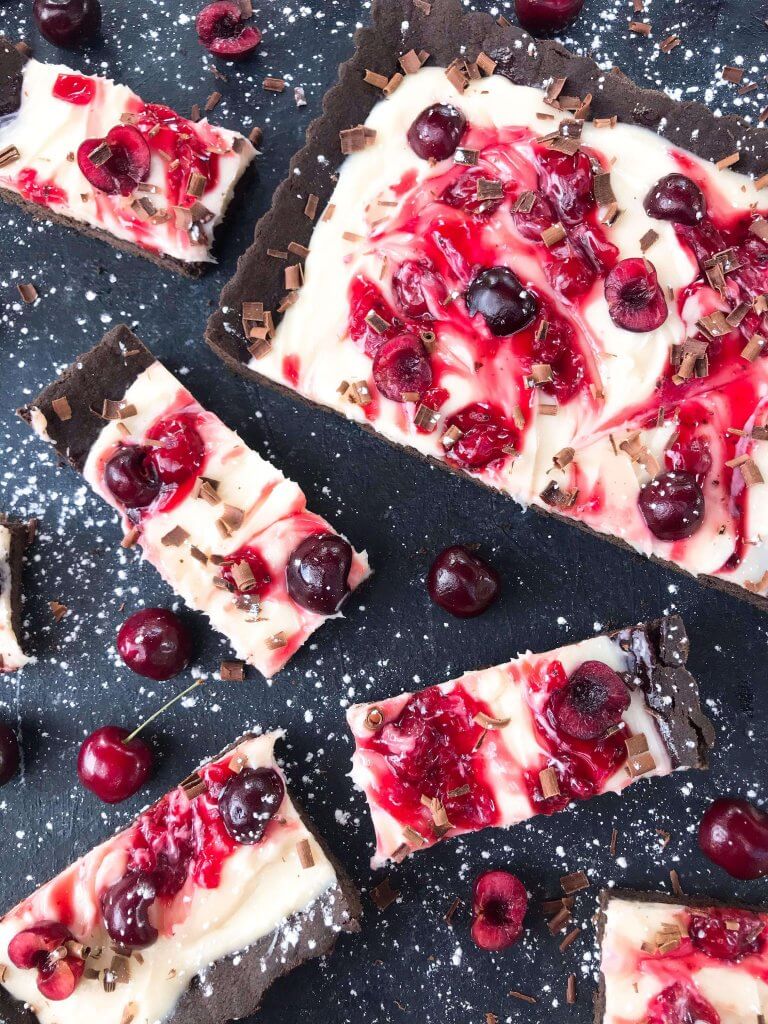 A quick and simple Black Forest Tart dessert recipe ready in 30 minutes. Chocolate, cherries, and cream are combined with a cocoa crust, cream cheese filling, and cherry pie swirl. #blackforestdesserts #tartrecipe #cherrydessert