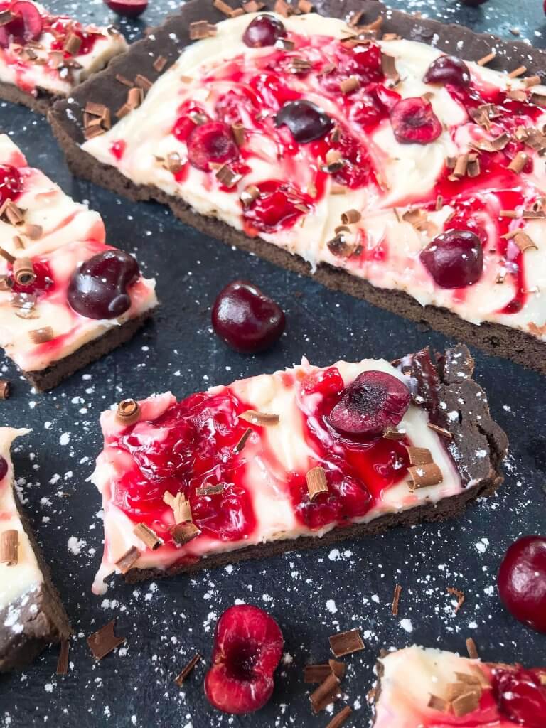 A quick and simple Black Forest Tart dessert recipe ready in 30 minutes. Chocolate, cherries, and cream are combined with a cocoa crust, cream cheese filling, and cherry pie swirl. #blackforestdesserts #tartrecipe #cherrydessert