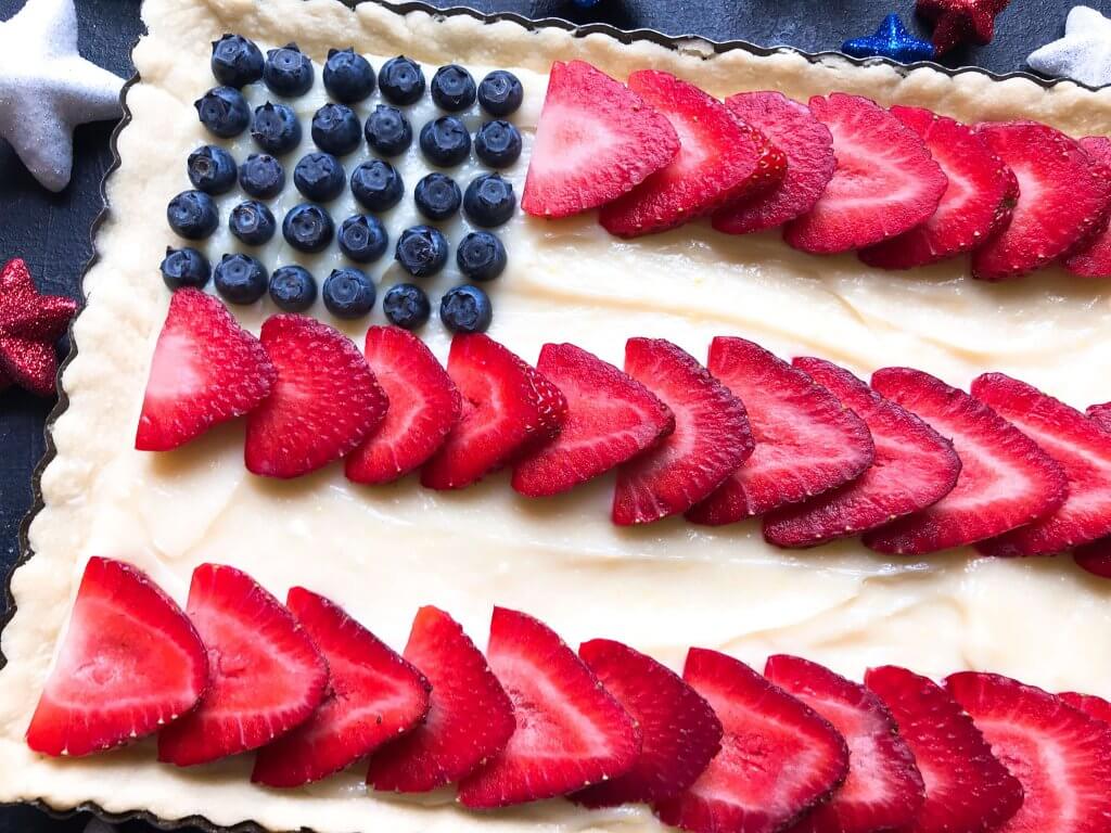 A quick and simple red, white, and blue dessert ready in 30 minutes. Patriotic American Flag Fruit Tart is a lemon cream cheese tart with fresh strawberries and blueberries. Great recipe for Labor Day, Memorial Day, and 4th of July BBQ or cookout. #americanrecipes #redwhitebluerecipes #redwhitebluedessert #fruittart