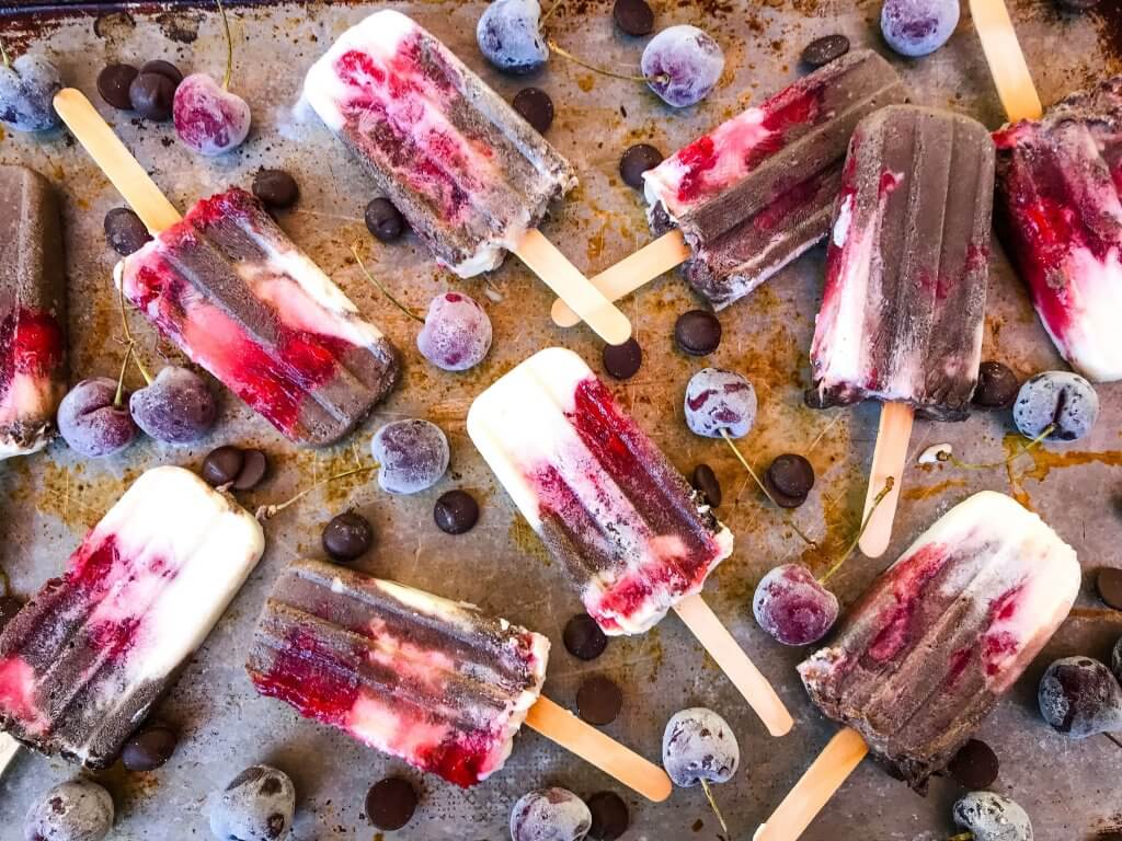 Black Forest Yogurt Popsicles are a simple and quick frozen dessert treat perfect for summer. Greek yogurt, cocoa chocolate yogurt, and cherry pie filling are layered for a healthy dessert. Vegetarian. #blackforest #cherrychocolate #popsicles
