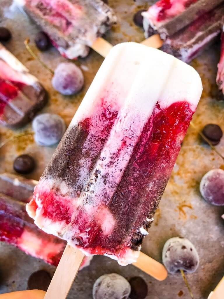 Black Forest Yogurt Popsicles are a simple and quick frozen dessert treat perfect for summer. Greek yogurt, cocoa chocolate yogurt, and cherry pie filling are layered for a healthy dessert. Vegetarian. #blackforest #cherrychocolate #popsicles