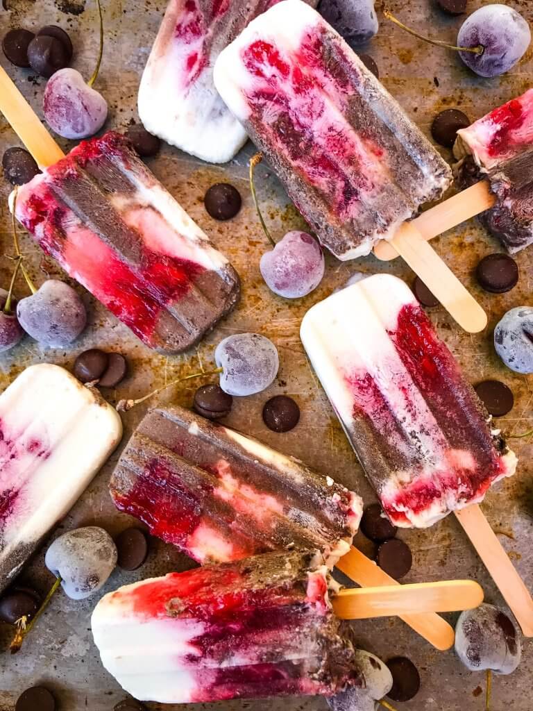 Black Forest Yogurt Popsicles are a simple and quick frozen dessert treat perfect for summer. Greek yogurt, cocoa chocolate yogurt, and cherry pie filling are layered for a healthy dessert. Vegetarian. #blackforest #cherrychocolate #popsicles