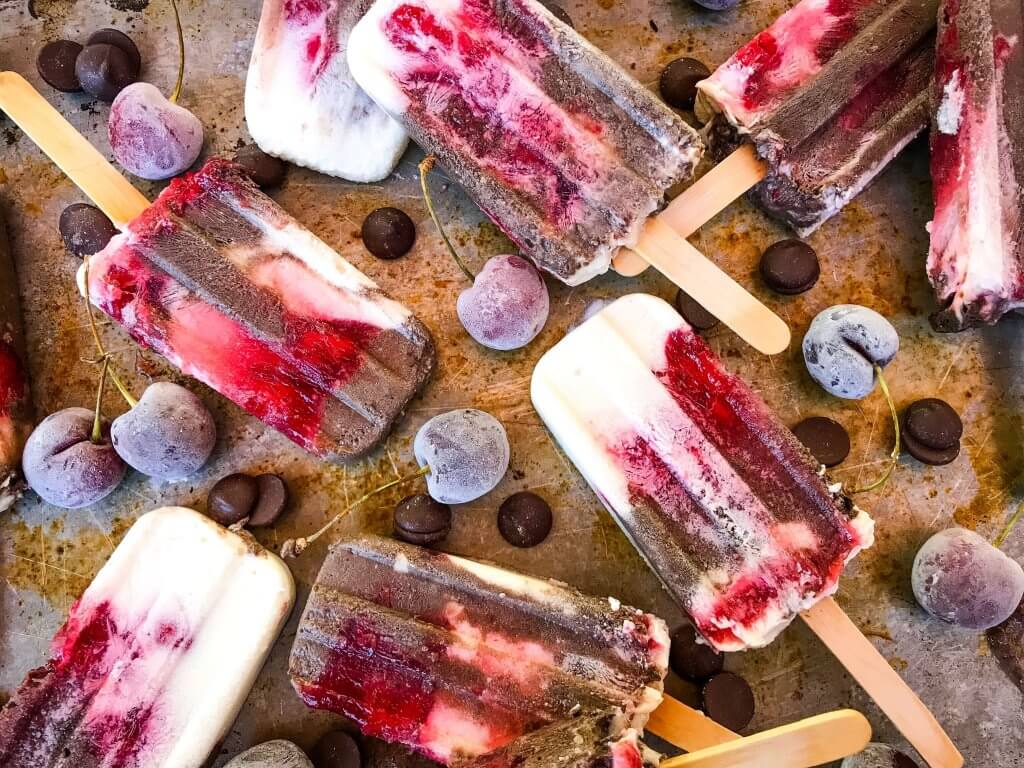 Black Forest Yogurt Popsicles are a simple and quick frozen dessert treat perfect for summer. Greek yogurt, cocoa chocolate yogurt, and cherry pie filling are layered for a healthy dessert. Vegetarian. #blackforest #cherrychocolate #popsicles