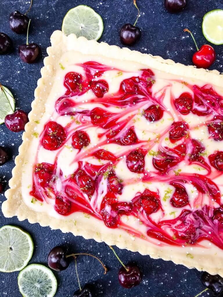 This fast and easy Cherry Limeade Tart is a perfect summer dessert recipe. A soft lime crust is filled with lime cream cheese filling and cherry pie swirls. #cherrylimeade #summerdessert #cherrydessert #tart