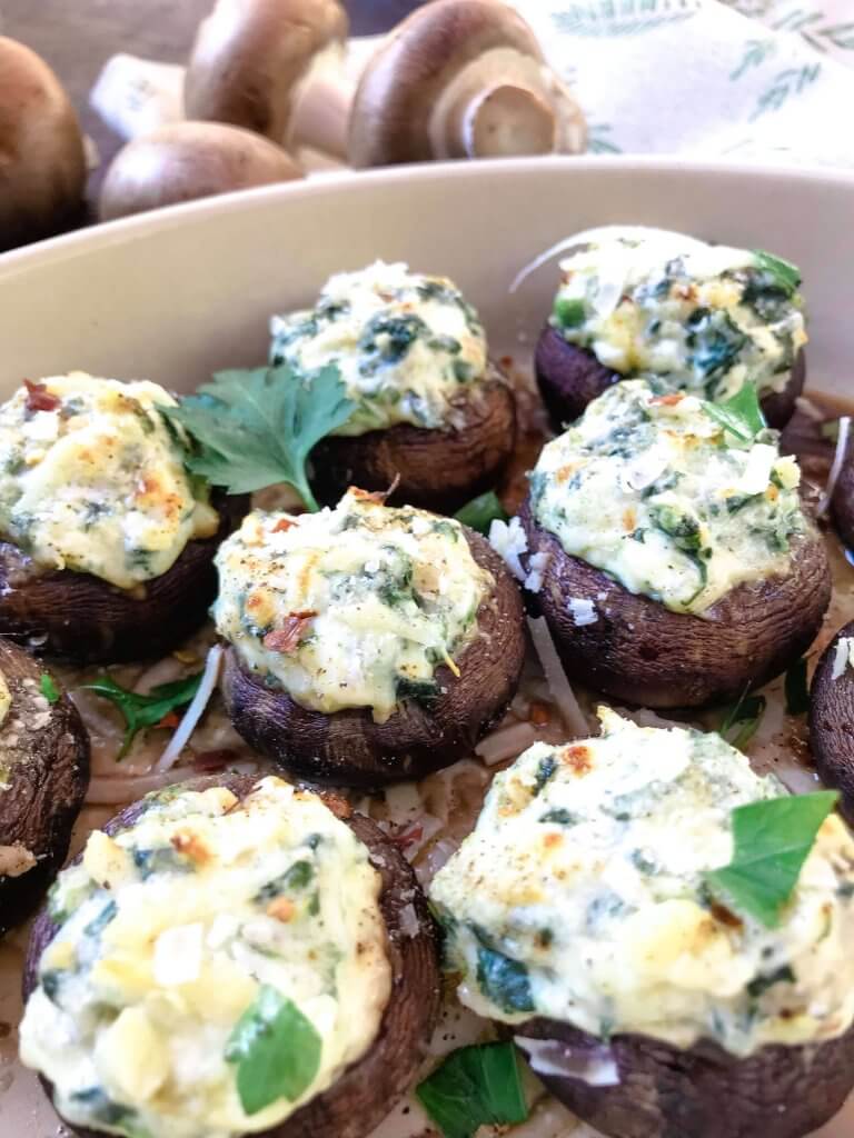 Fast and easy appetizer recipe for party entertaining finger food and game day. Gluten free, low carb keto, and vegetarian, these Spinach Artichoke Dip Stuffed Mushrooms are filled with cheese, spinach, and artichoke hearts. #stuffedmushrooms #glutenfreerecipes #spinachartichokedip