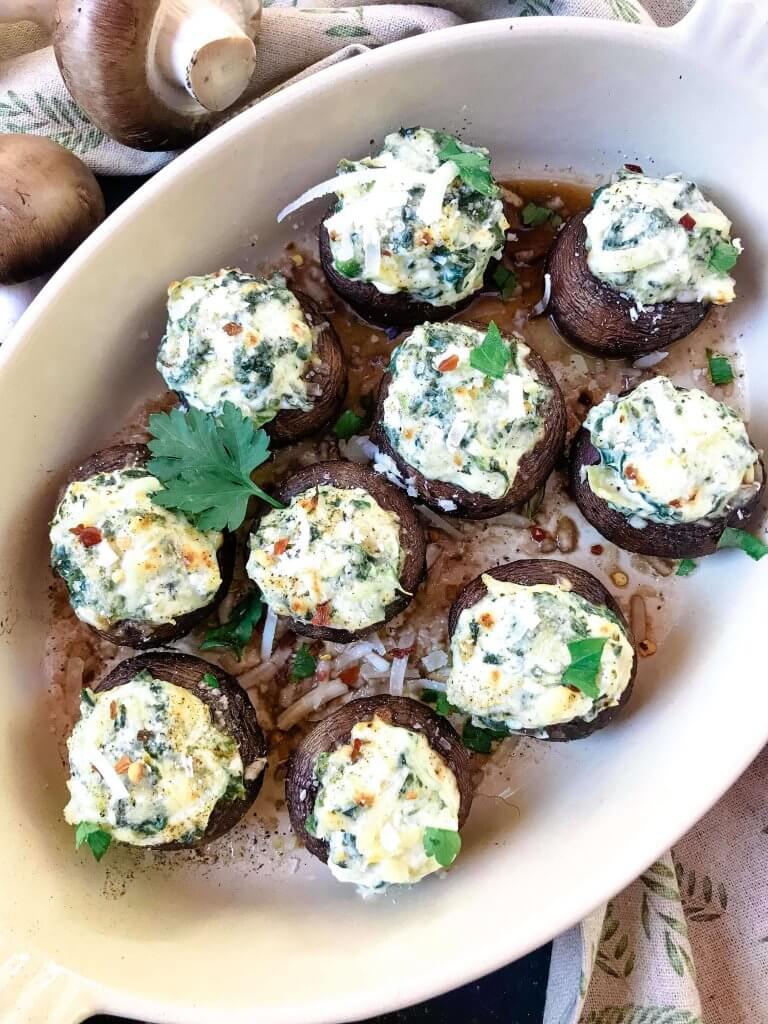 Fast and easy appetizer recipe for party entertaining finger food and game day. Gluten free, low carb keto, and vegetarian, these Spinach Artichoke Dip Stuffed Mushrooms are filled with cheese, spinach, and artichoke hearts. #stuffedmushrooms #glutenfreerecipes #spinachartichokedip