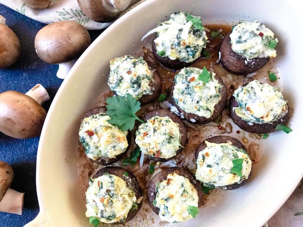 Fast and easy appetizer recipe for party entertaining finger food and game day. Gluten free, low carb keto, and vegetarian, these Spinach Artichoke Dip Stuffed Mushrooms are filled with cheese, spinach, and artichoke hearts. #stuffedmushrooms #glutenfreerecipes #spinachartichokedip
