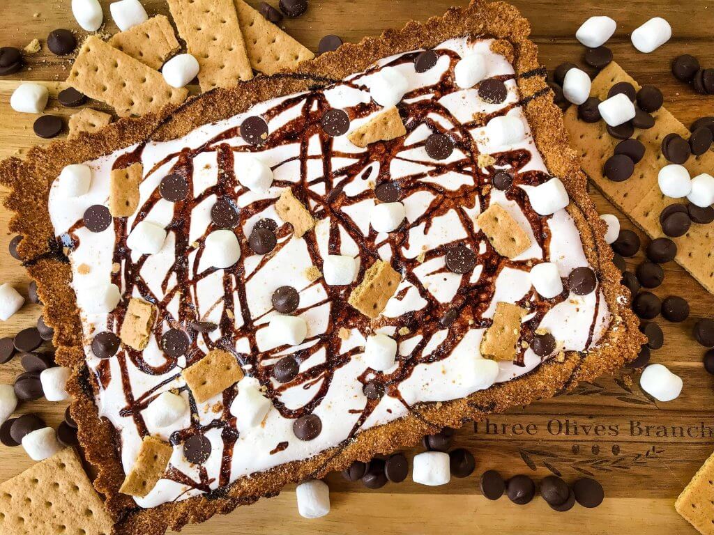 A S'mores Tart for summer dessert recipes. A graham cracker crust is filled with melted chocolate, marshmallow fluff, and s'mores ingredients. Simple and easy. #smores #tartrecipe