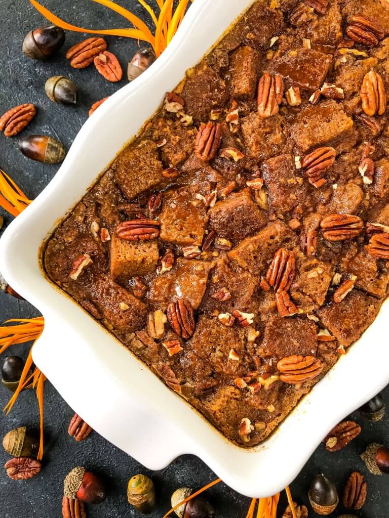 A dish of Pumpkin Bread Pudding after baking in a white dish surrounded by pecans
