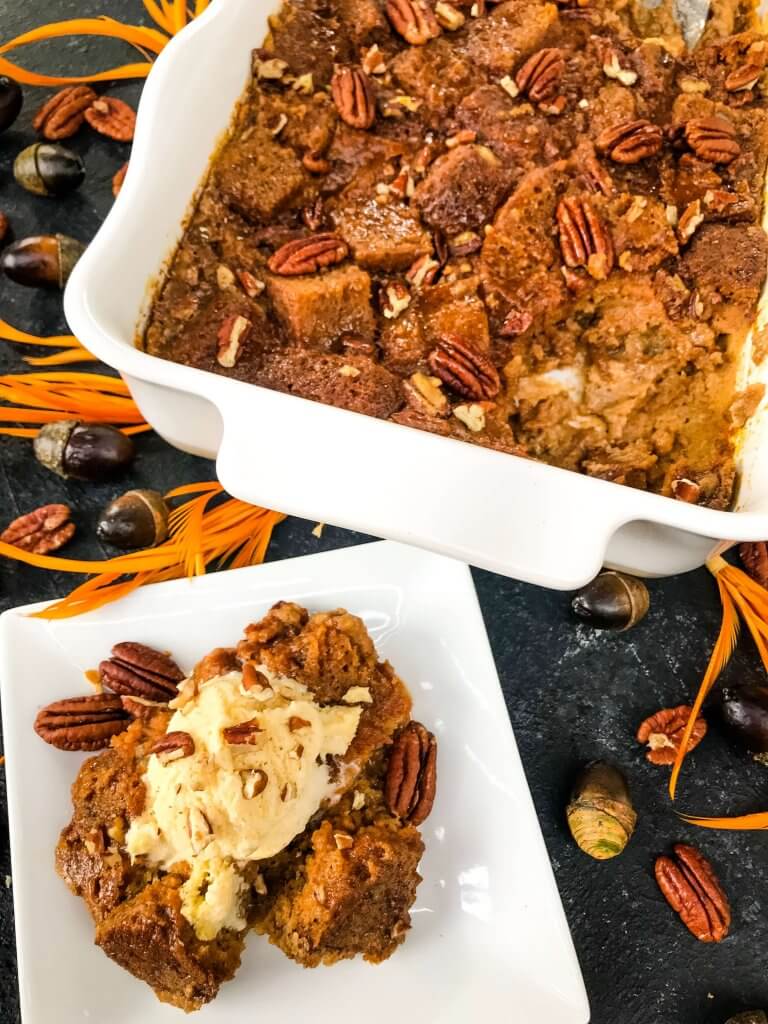 A portion of Pumpkin Bread Pudding removed from the baking dish and on a white plate with ice cream