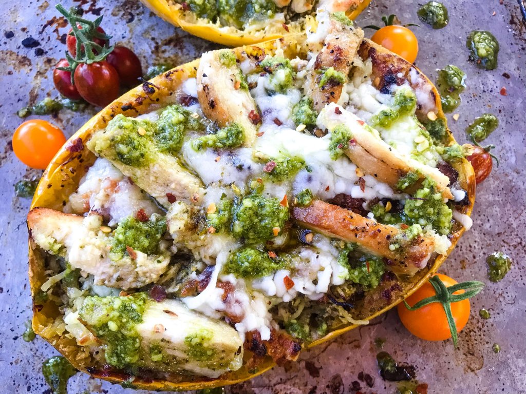 A half of a Keto Low Carb Cheesy Chicken Pesto Spaghetti Squash