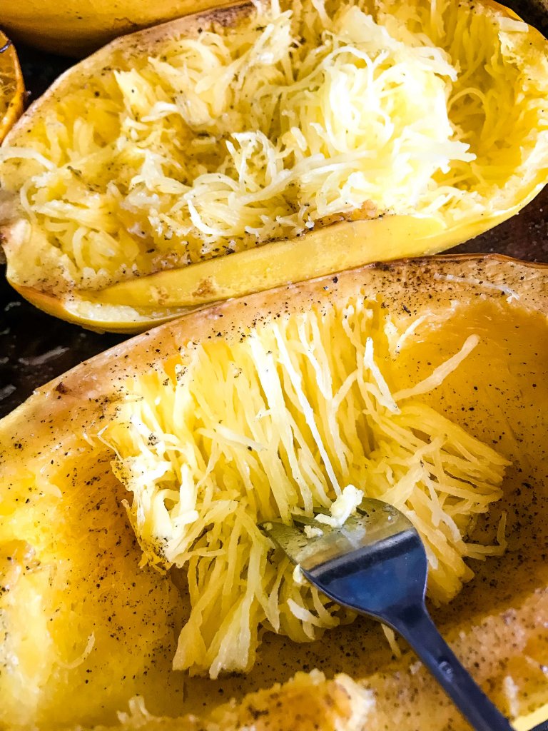 A fork shredding a spaghetti squash to make the noodle strands